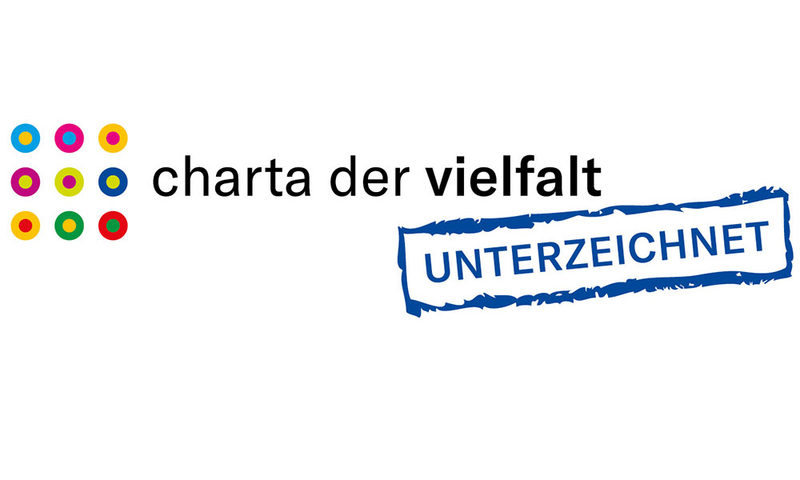 Charta der Vielfalt- Logo mit blauer/schwarzer Schrift, weißer Hintergrund und bunten Punkten.