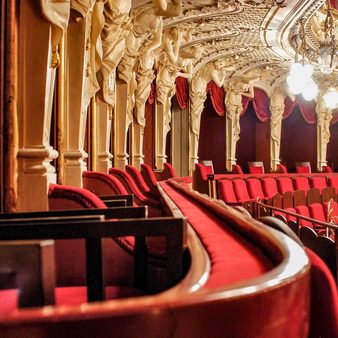 Blick auf die samtüberzogenen Sitzreihen im Rang des Hessischen Staatstheaters Wiesbaden sowie die verzierten Portale der Logen.